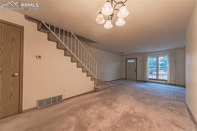 foyer featuring carpet flooring, a textured ceiling, and a notable chandelier