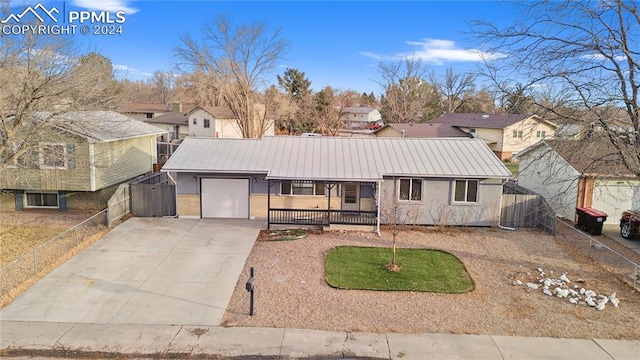 view of front facade featuring fence, concrete driveway, metal roof, a garage, and a standing seam roof