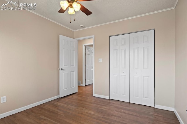 unfurnished bedroom featuring dark wood-type flooring, ceiling fan, a closet, and crown molding