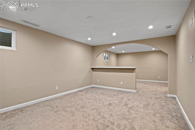 below grade area featuring visible vents, recessed lighting, carpet floors, arched walkways, and baseboards