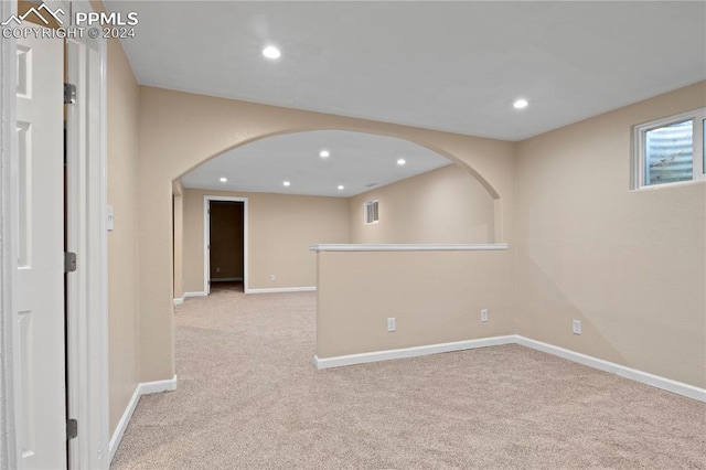 spare room featuring arched walkways, carpet flooring, recessed lighting, and baseboards