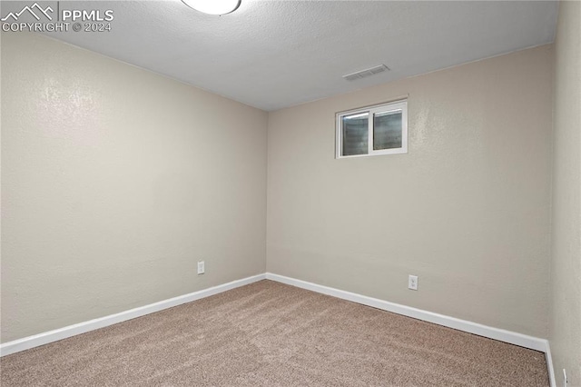 unfurnished room with carpet flooring, visible vents, baseboards, and a textured ceiling