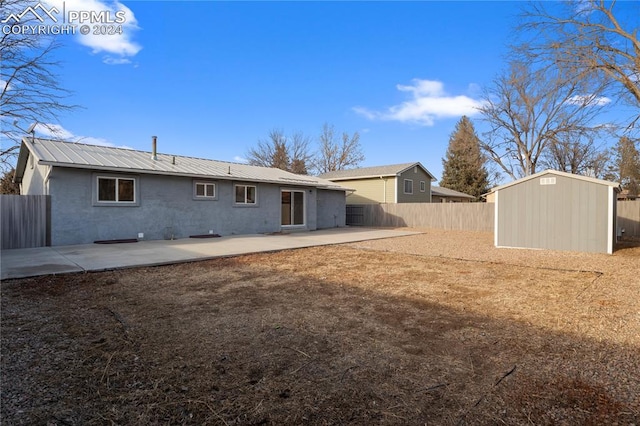 back of house featuring metal roof, a storage shed, a fenced backyard, a patio area, and an outbuilding