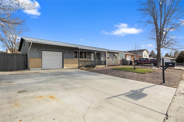 single story home with brick siding, fence, covered porch, metal roof, and an attached garage