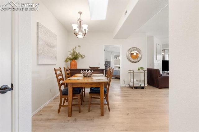 dining area with light hardwood / wood-style flooring and an inviting chandelier