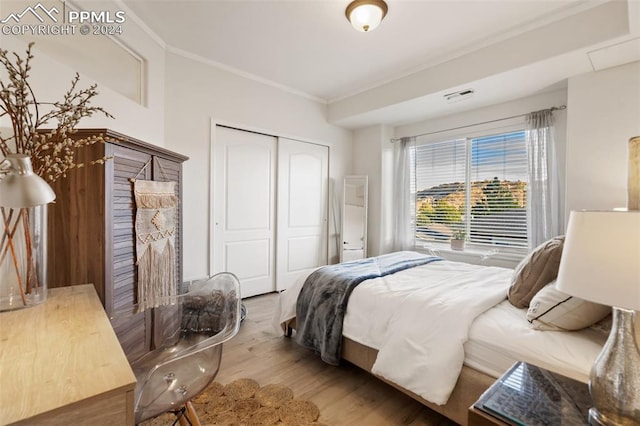 bedroom with hardwood / wood-style floors, crown molding, and a closet