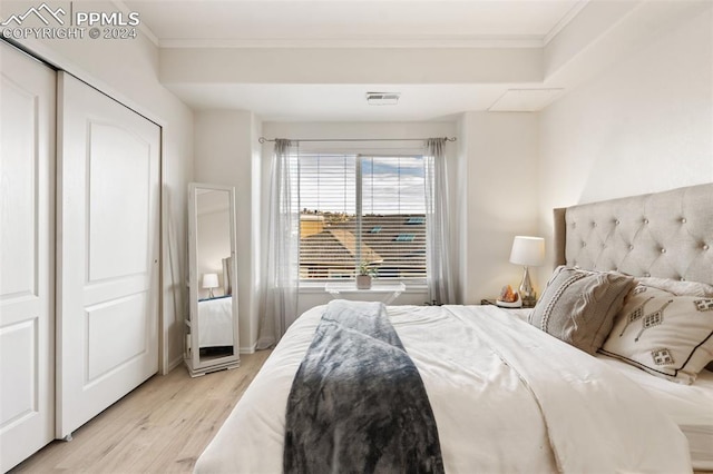 bedroom featuring a closet, ornamental molding, and light hardwood / wood-style flooring