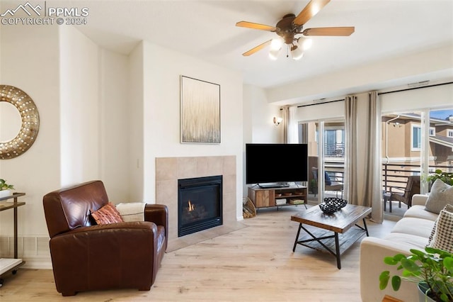 living room featuring a fireplace, light wood-type flooring, and ceiling fan