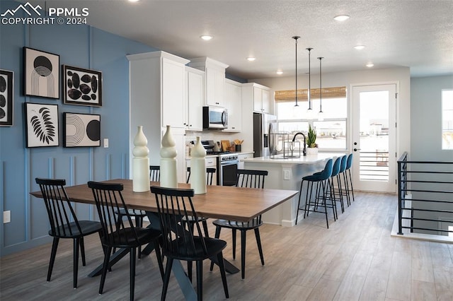 dining room with a textured ceiling, sink, and light hardwood / wood-style flooring