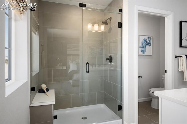 bathroom featuring tile patterned flooring, a shower with door, vanity, and toilet