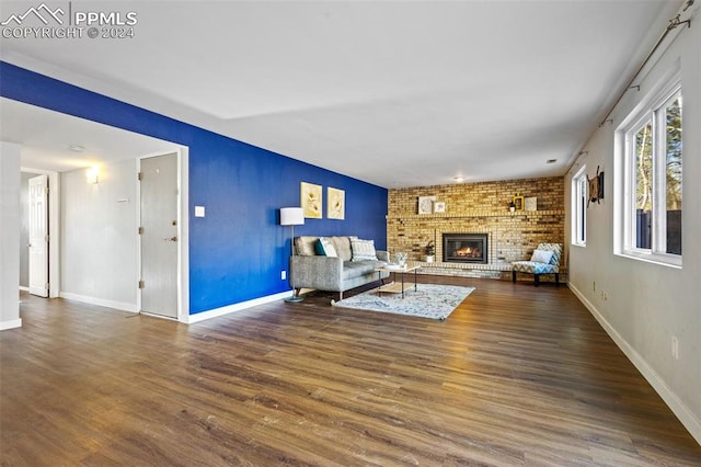 living room with a fireplace, dark hardwood / wood-style flooring, and brick wall