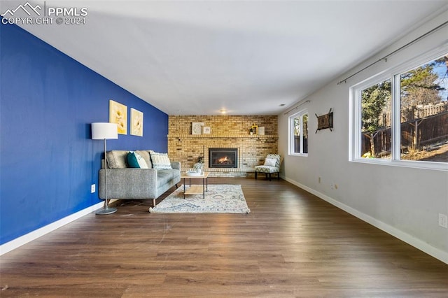 unfurnished living room featuring wood-type flooring, brick wall, and a brick fireplace