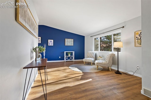 sitting room with hardwood / wood-style floors and vaulted ceiling