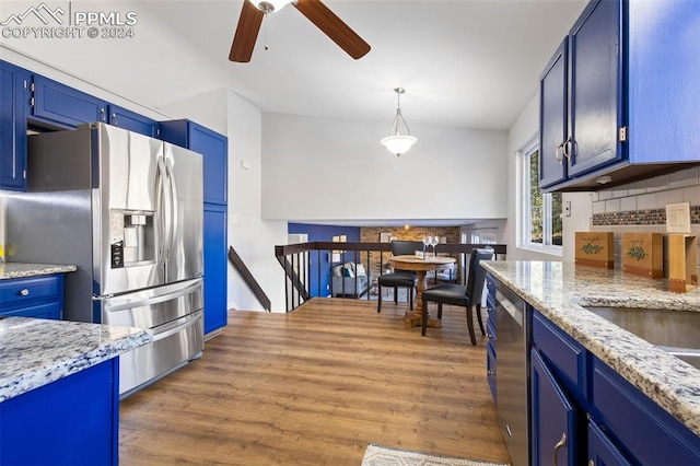 kitchen with decorative backsplash, appliances with stainless steel finishes, dark hardwood / wood-style flooring, blue cabinetry, and decorative light fixtures