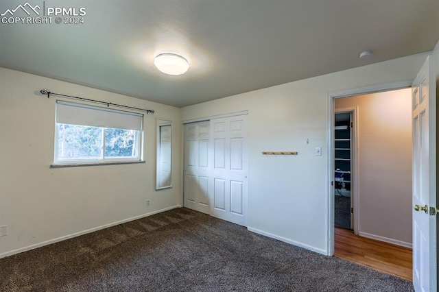 unfurnished bedroom with dark colored carpet and a closet