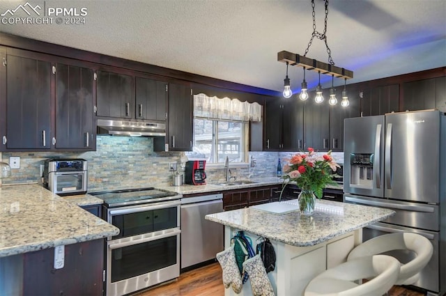 kitchen featuring pendant lighting, a center island, sink, decorative backsplash, and stainless steel appliances