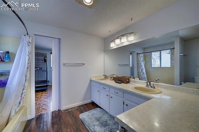 bathroom featuring vanity, a textured ceiling, hardwood / wood-style flooring, and shower / bath combo with shower curtain