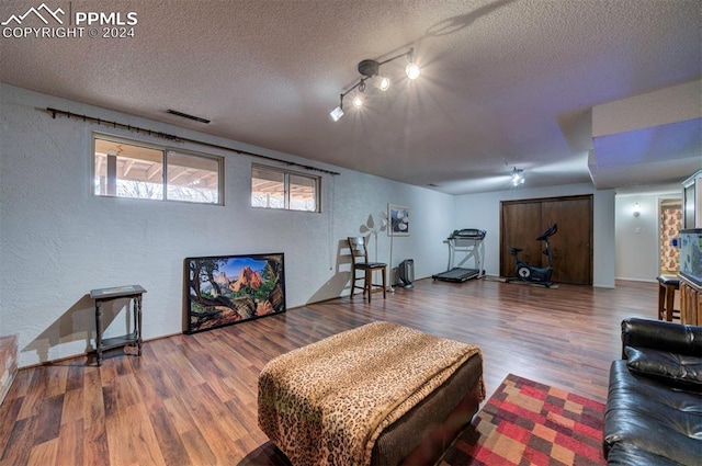 living room featuring wood-type flooring, a textured ceiling, and rail lighting