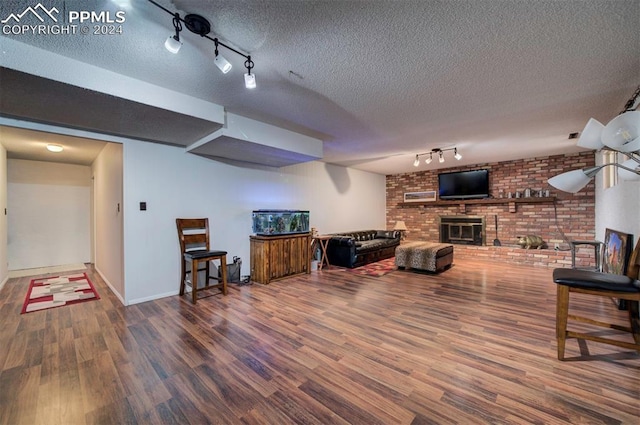 living room with a textured ceiling, hardwood / wood-style flooring, and a brick fireplace