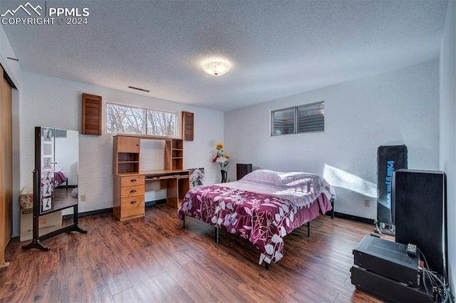 bedroom featuring a textured ceiling and dark hardwood / wood-style floors