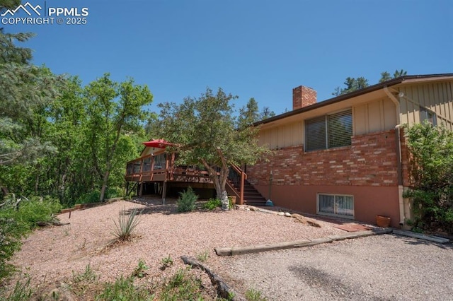 1210 W Woodmen Rd, Colorado Springs, CO 80919 - back of property featuring brick siding, a chimney, a deck, and stairway
