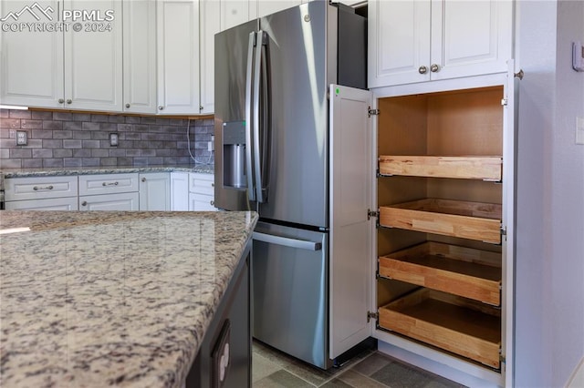 kitchen featuring white cabinets, stainless steel refrigerator with ice dispenser, decorative backsplash, and light stone countertops