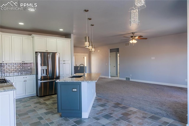 kitchen featuring white cabinetry, stainless steel fridge, sink, and pendant lighting