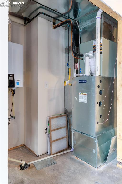 utility room featuring heating unit and water heater