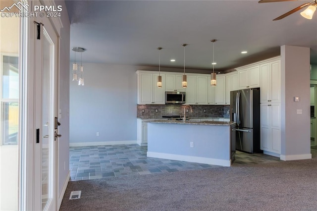 kitchen featuring decorative backsplash, an island with sink, stainless steel appliances, and decorative light fixtures