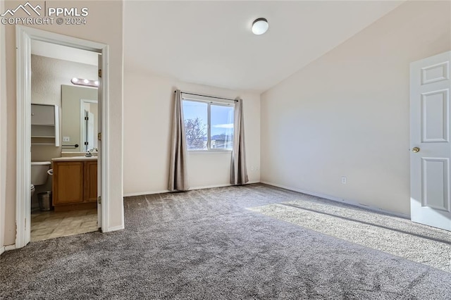 unfurnished bedroom with carpet, ensuite bathroom, vaulted ceiling, and sink