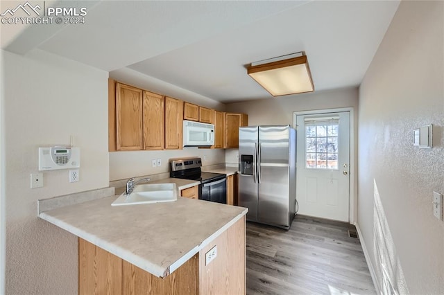 kitchen with kitchen peninsula, sink, stainless steel appliances, and light hardwood / wood-style flooring