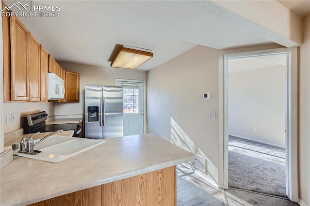 kitchen with kitchen peninsula, stainless steel fridge with ice dispenser, stove, and sink