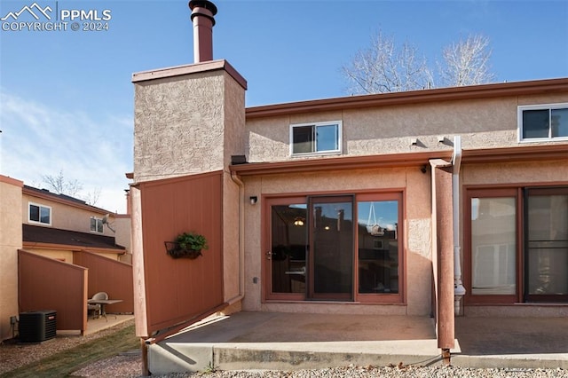 rear view of property with cooling unit and a patio