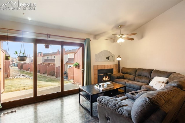 living room featuring ceiling fan, a wealth of natural light, a tile fireplace, and hardwood / wood-style floors