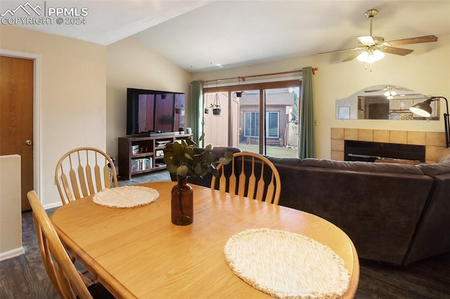 dining room featuring vaulted ceiling, ceiling fan, dark hardwood / wood-style flooring, and a fireplace