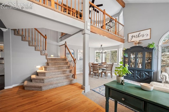 stairs with a high ceiling, a notable chandelier, and hardwood / wood-style floors