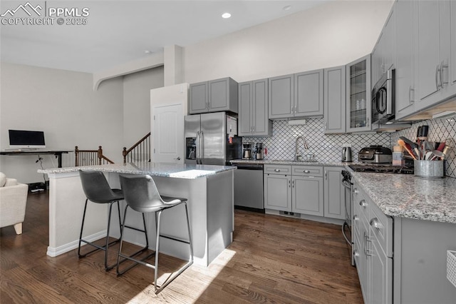 kitchen featuring appliances with stainless steel finishes, a center island, light stone counters, and sink