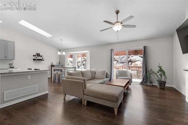 living room featuring dark hardwood / wood-style flooring, ceiling fan with notable chandelier, lofted ceiling with skylight, and a wealth of natural light