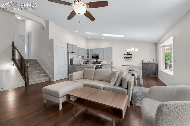 living room with ceiling fan with notable chandelier, dark hardwood / wood-style floors, and vaulted ceiling