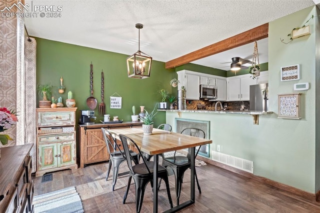 dining area with ceiling fan with notable chandelier, beam ceiling, dark hardwood / wood-style flooring, and a textured ceiling