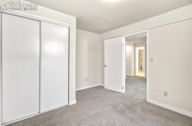 unfurnished bedroom featuring a closet and light colored carpet