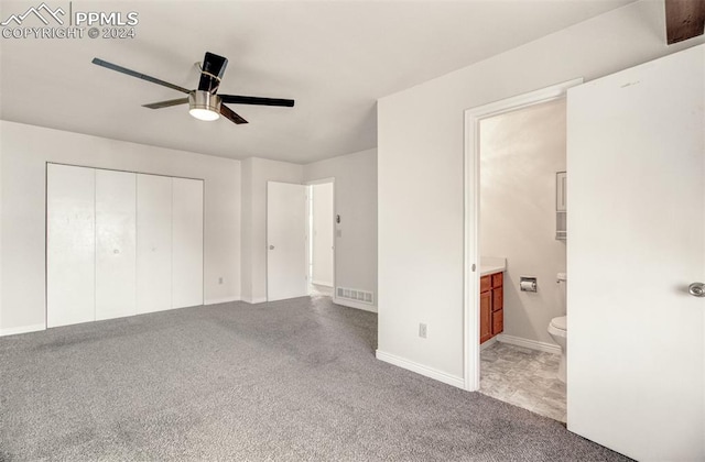 unfurnished bedroom featuring carpet flooring, ensuite bathroom, ceiling fan, and a closet