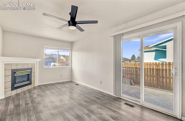 unfurnished living room featuring a tile fireplace, ceiling fan, and hardwood / wood-style flooring