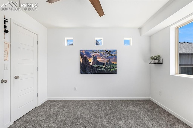 empty room with dark colored carpet and ceiling fan