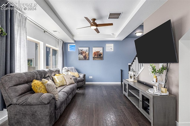 living room featuring a raised ceiling, ceiling fan, dark hardwood / wood-style flooring, and a healthy amount of sunlight