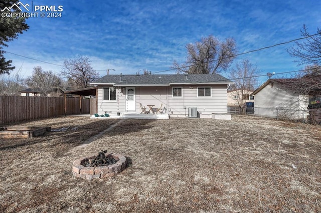 rear view of house featuring a carport and an outdoor fire pit