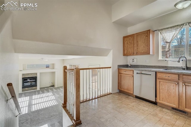 kitchen featuring dishwasher, a fireplace, and sink