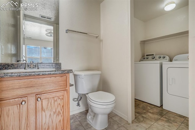 bathroom with washer and dryer, vanity, a textured ceiling, and toilet