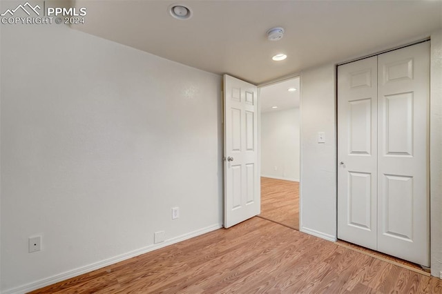 unfurnished bedroom with light wood-type flooring and a closet