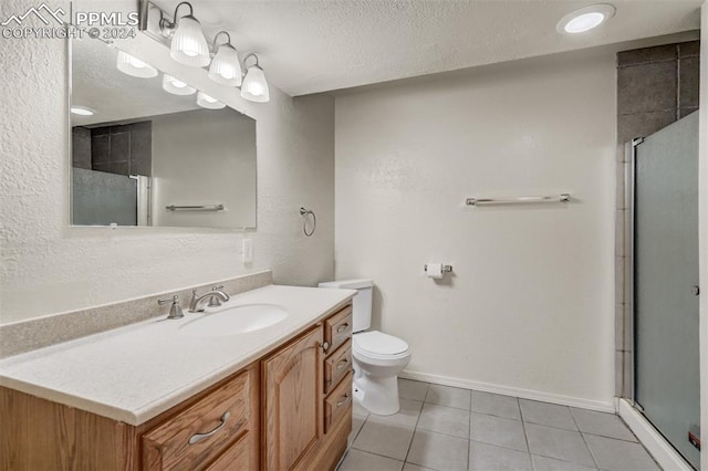 bathroom with tile patterned floors, a shower with door, vanity, and toilet